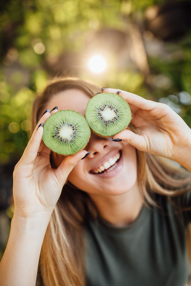 Femme qui sourit avec un kiwi